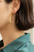 Close-up of a beautiful woman wearing gold hoop earrings with a blurred beautiful home
 background
